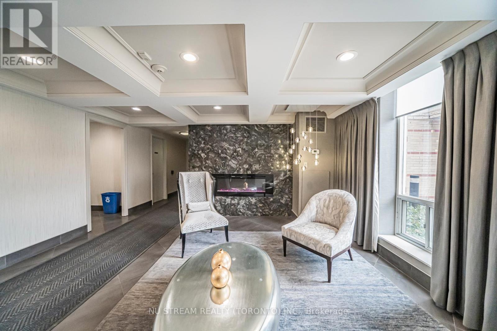 A modern living room with a stone fireplace and two white chairs.