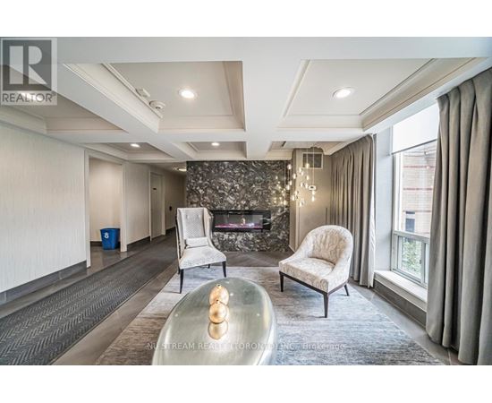 A modern living room with a stone fireplace and two white chairs.