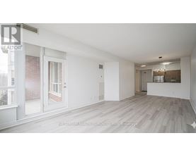 A spacious room with a sliding glass door and a view of a brick building outside.