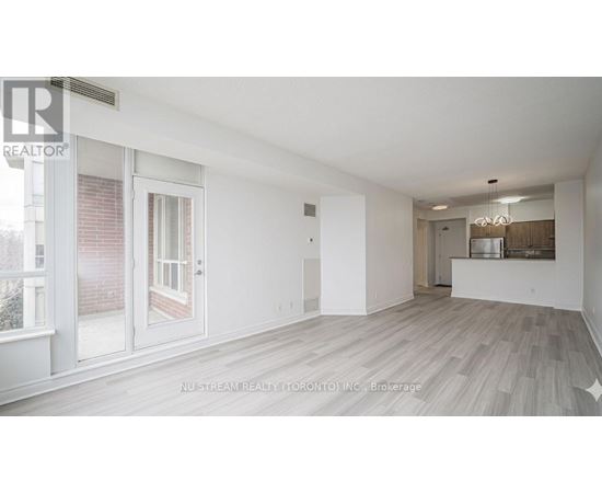 A spacious room with a sliding glass door and a view of a brick building outside.