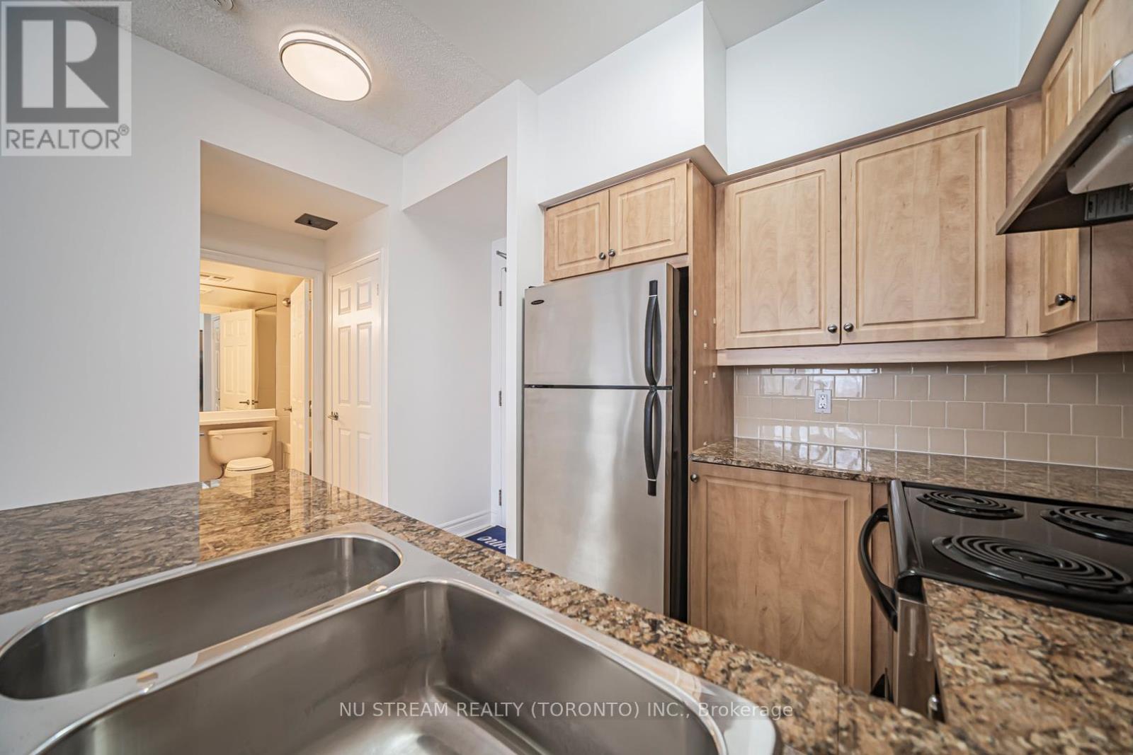A kitchen with a stainless steel refrigerator and a granite countertop.