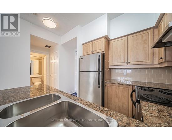 A kitchen with a stainless steel refrigerator and a granite countertop.