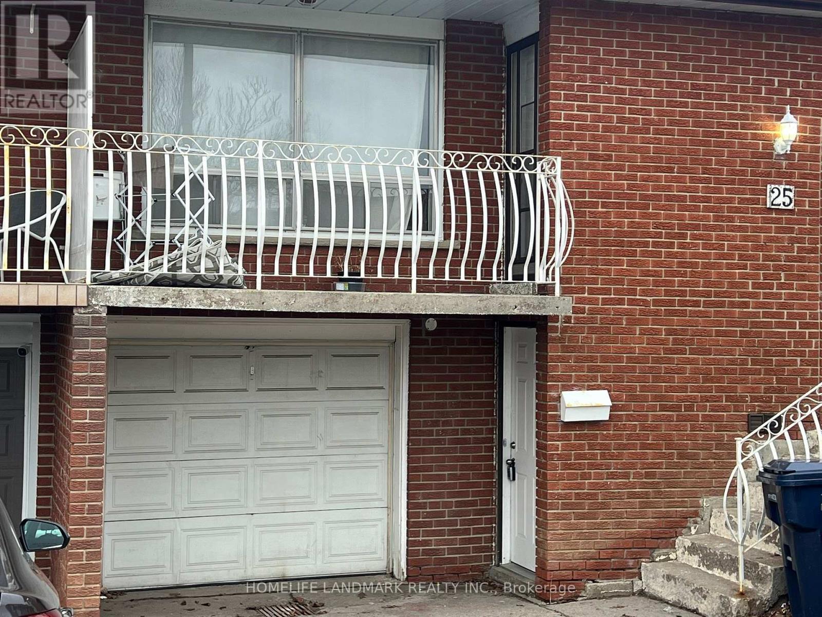 A red brick house with a white garage door and a balcony.