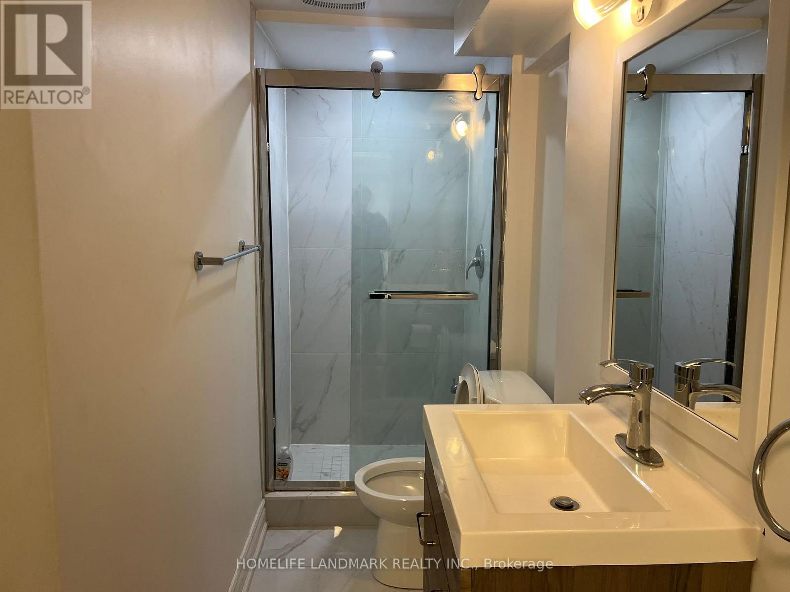 A bathroom with a sink, mirror, and shower.