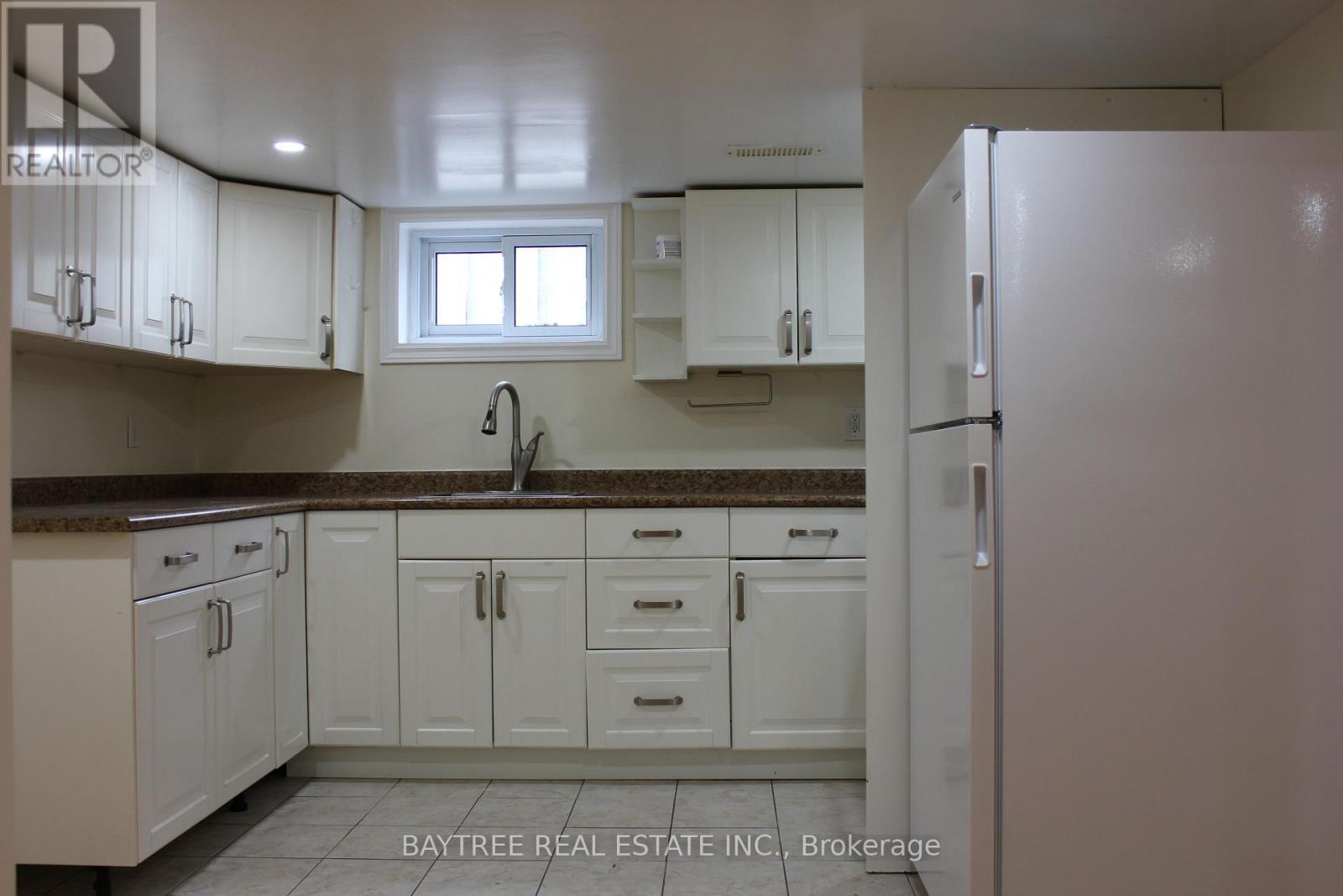 A kitchen with white cabinets and a refrigerator.