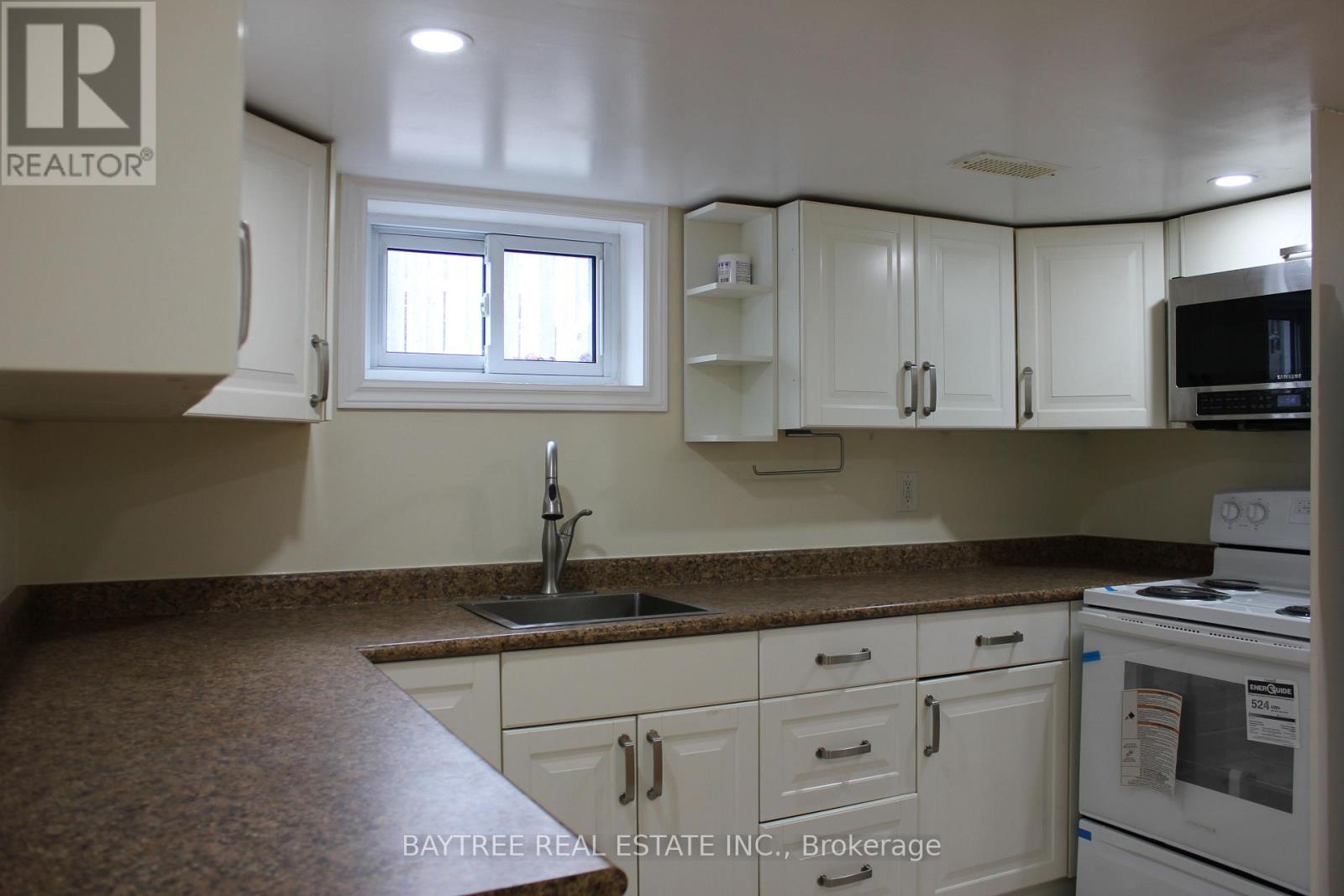 A kitchen with white cabinets and a brown countertop.