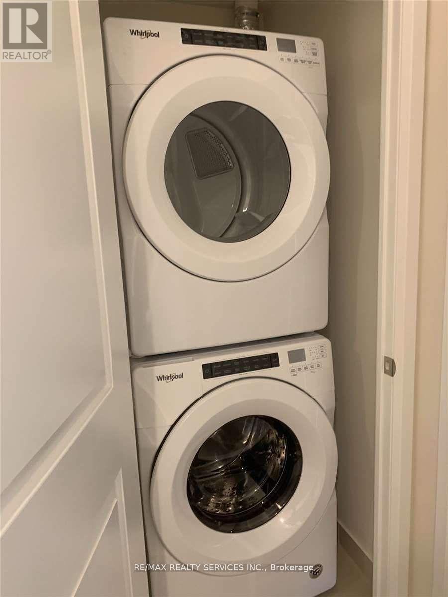 Two white Whirlpool washing machines stacked on top of each other in a laundry room.