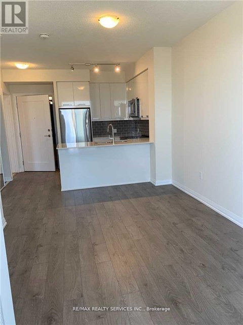 A kitchen with white cabinets and a wooden floor.