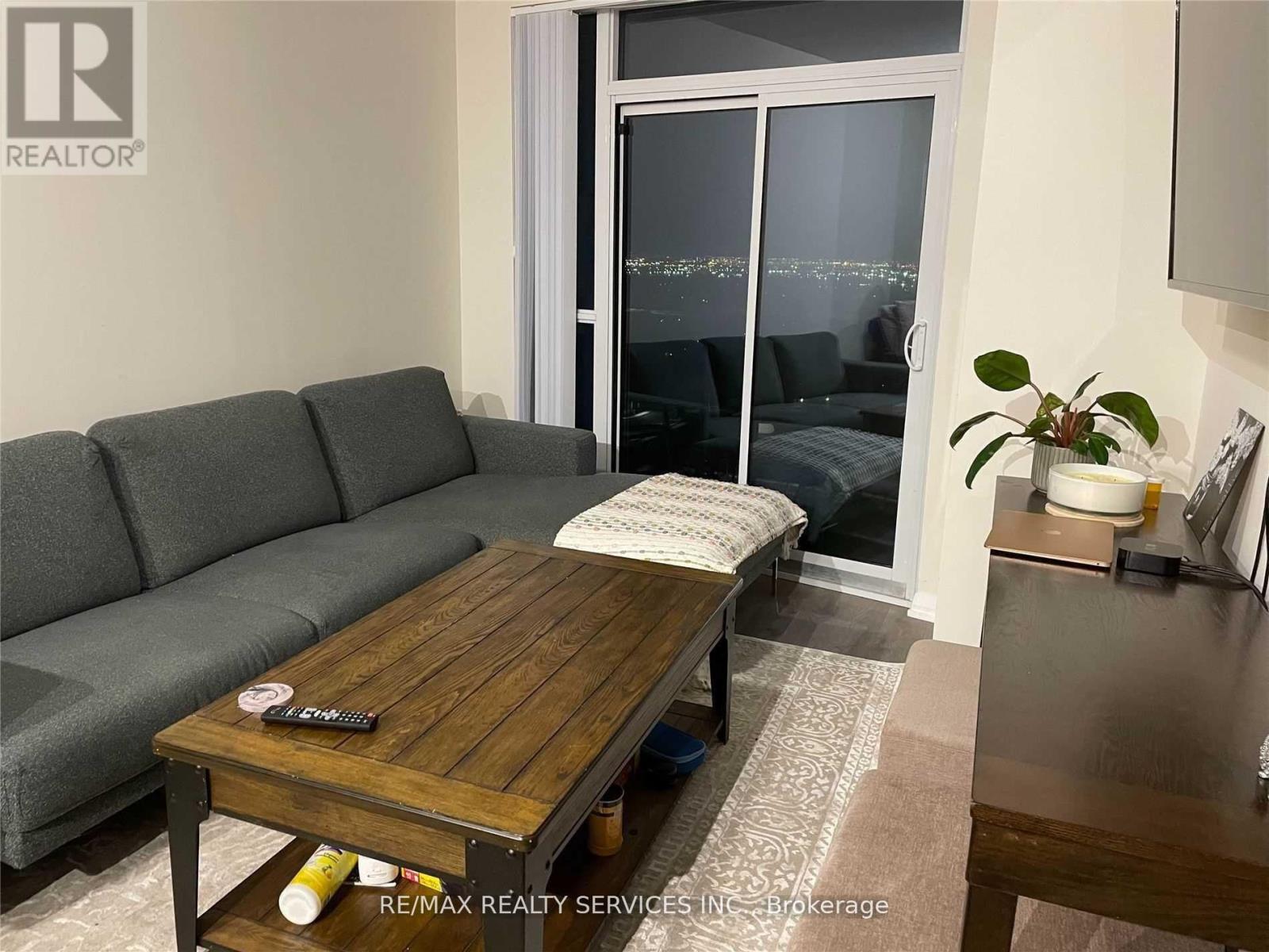 A living room with a grey couch, a wooden coffee table, and a sliding glass door.