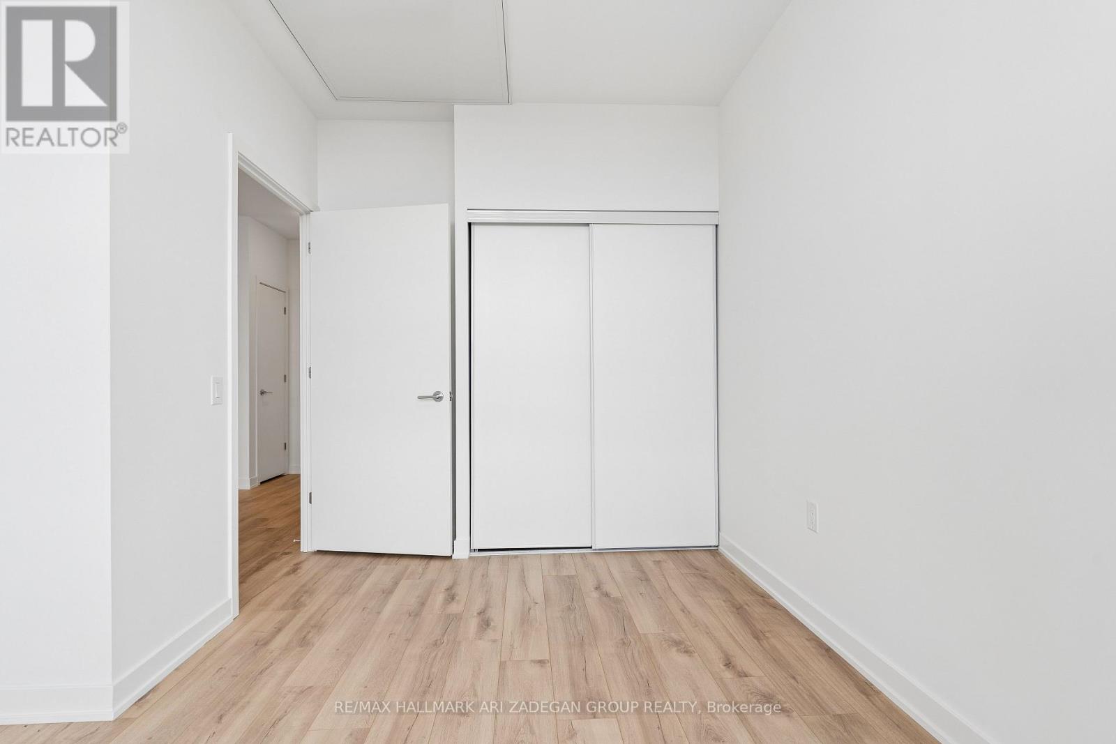 A white bedroom with a large closet and a doorway leading to another room.