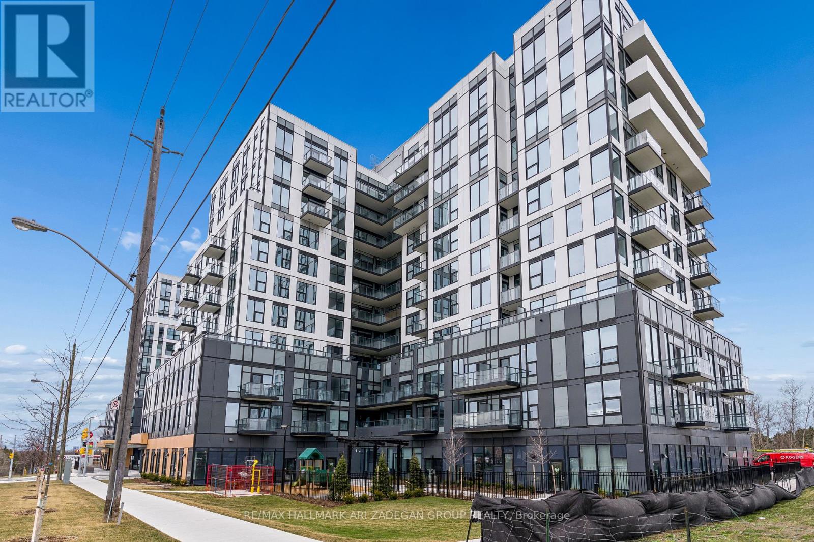 A modern multi-story residential building with balconies and a clear blue sky above.