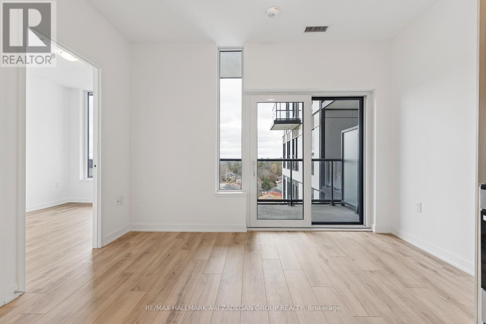 A spacious room with wooden flooring and a large window.