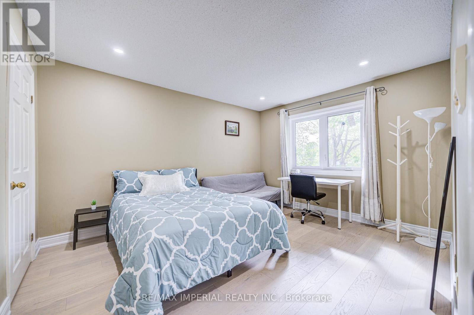 A bedroom with a bed, desk, chair, and window.