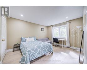 A bedroom with a bed, desk, chair, and window.