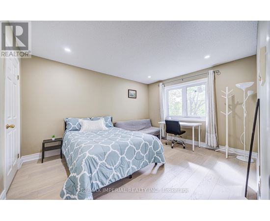 A bedroom with a bed, desk, chair, and window.
