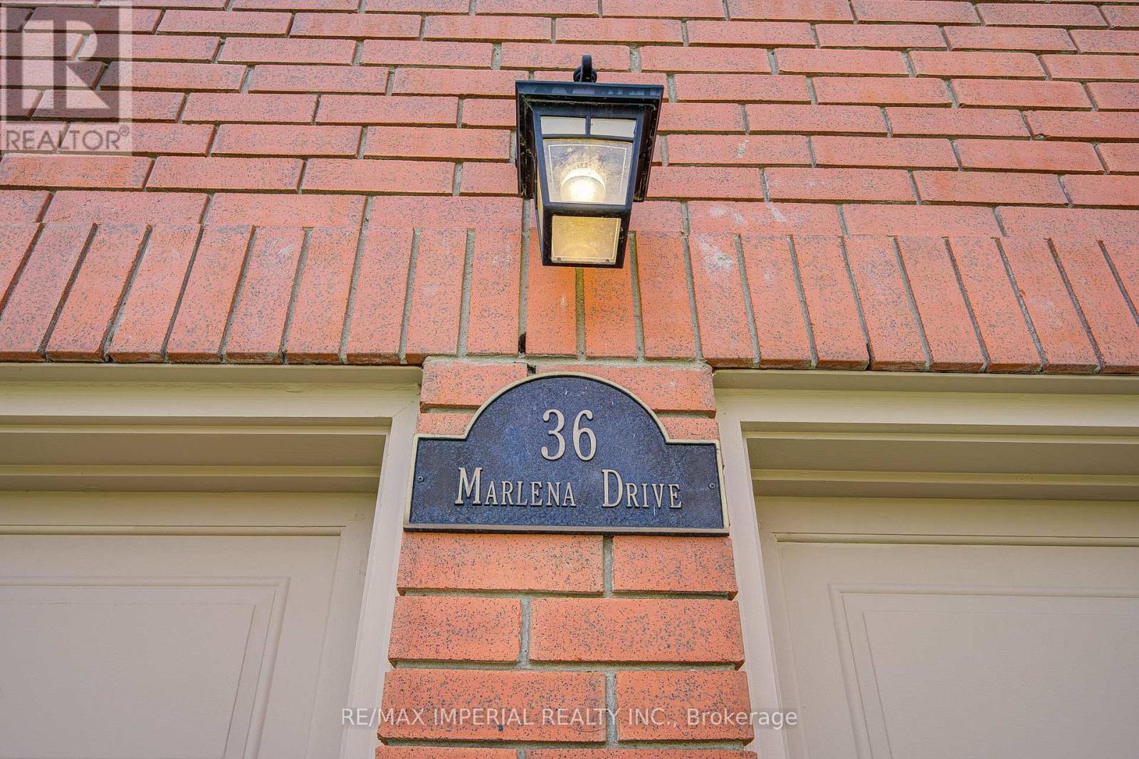 A house number 36 with a signboard and a light on the wall.