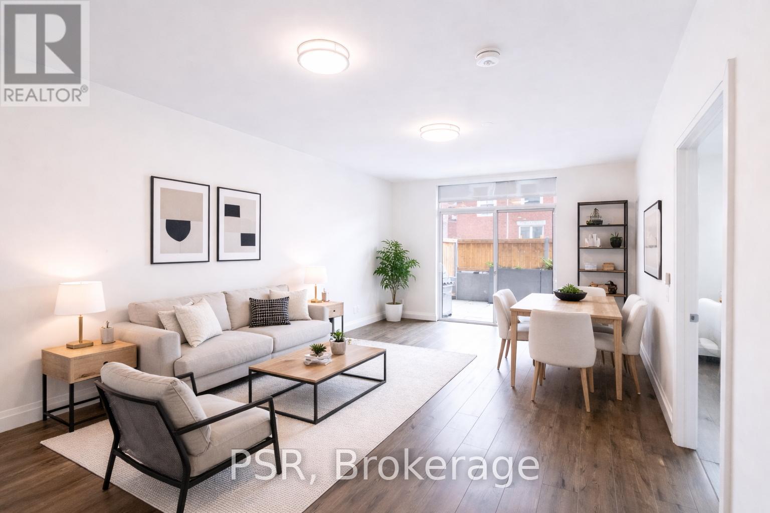 A well-lit living room with a couch, chairs, and a dining table.