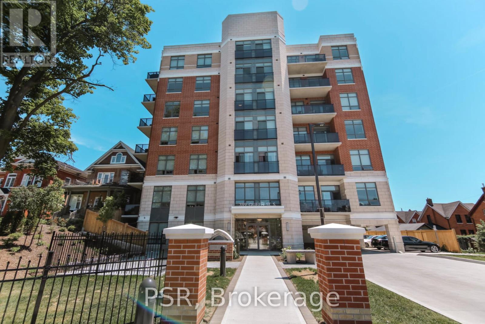 A tall apartment building with a brick facade and a black gate in front.