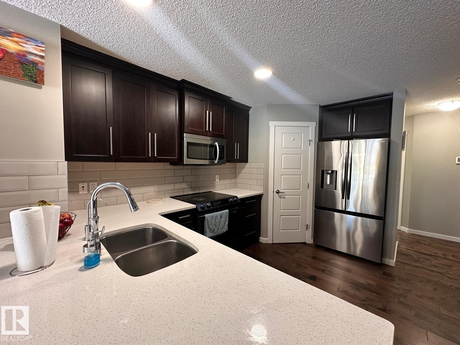 A kitchen with a sink and a refrigerator.