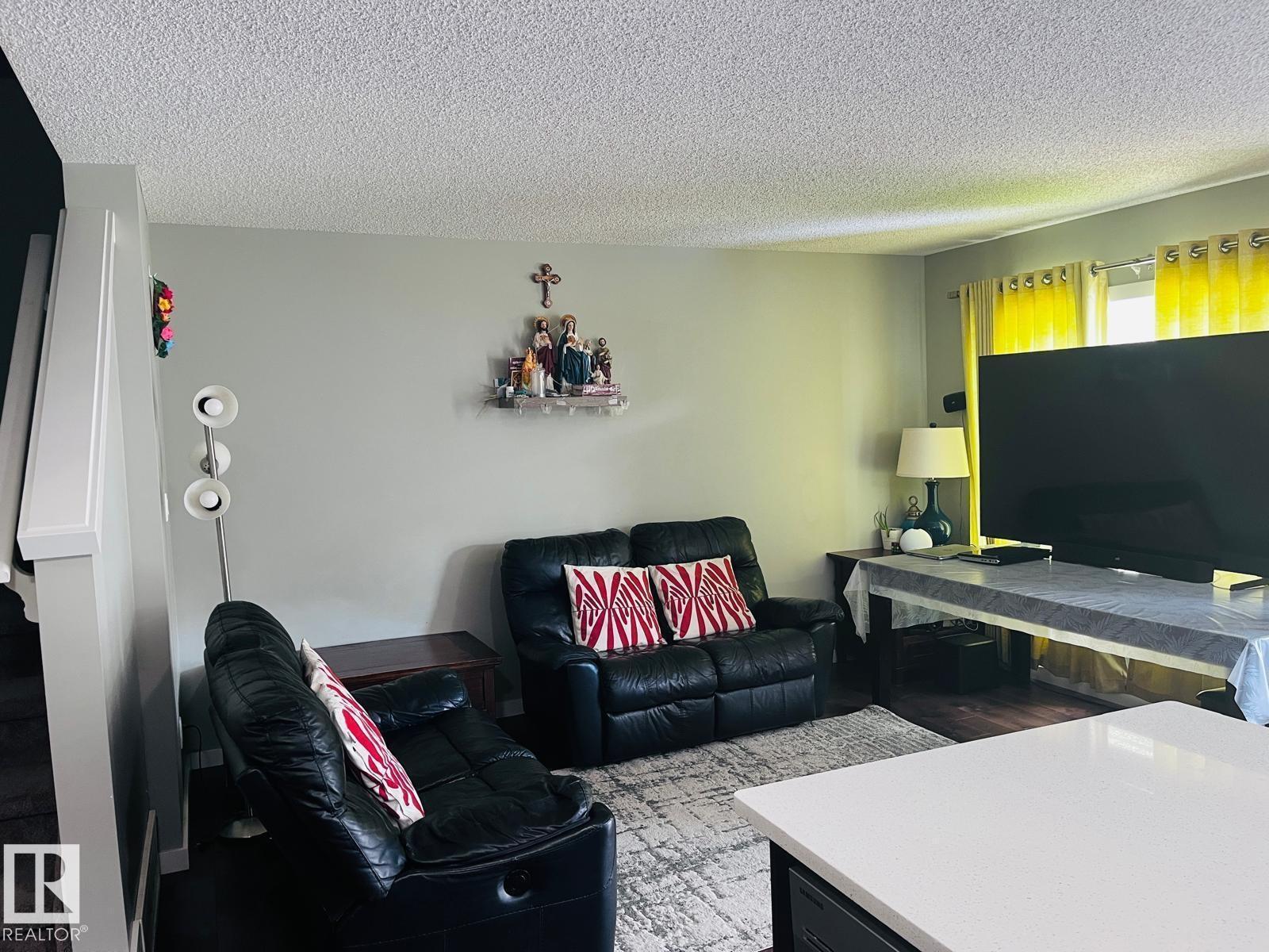 A living room with a black leather couch and a television.