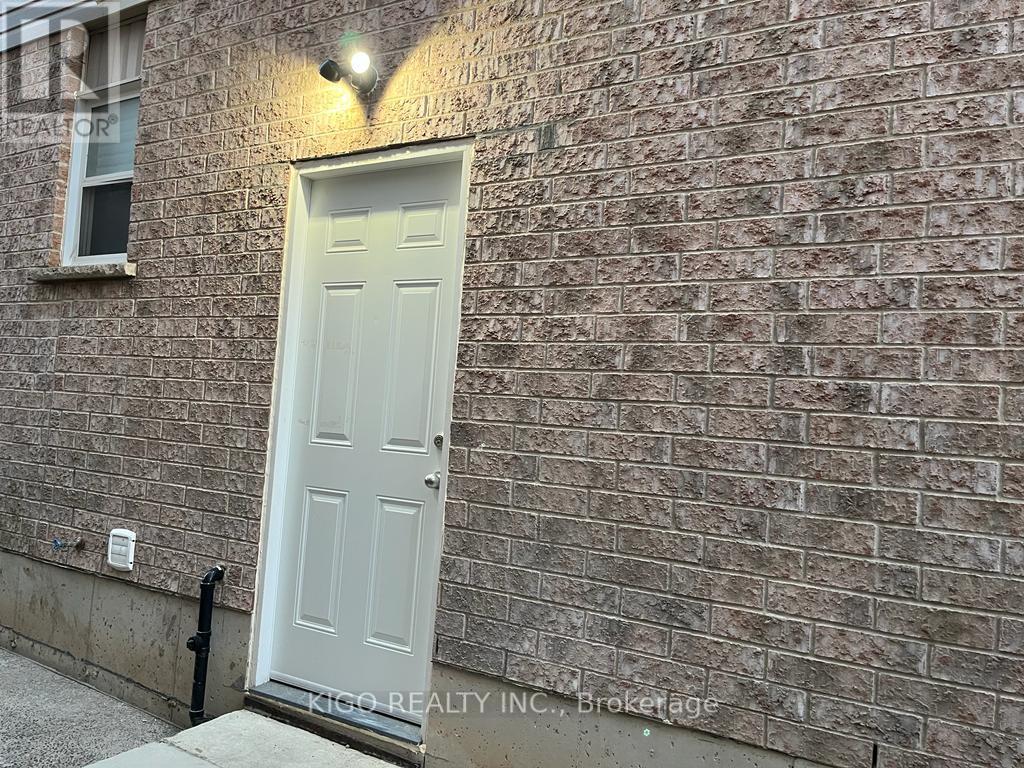 A white door is on the left side of a brick wall.