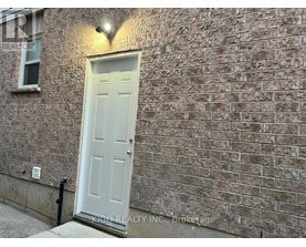 A white door is on the left side of a brick wall.