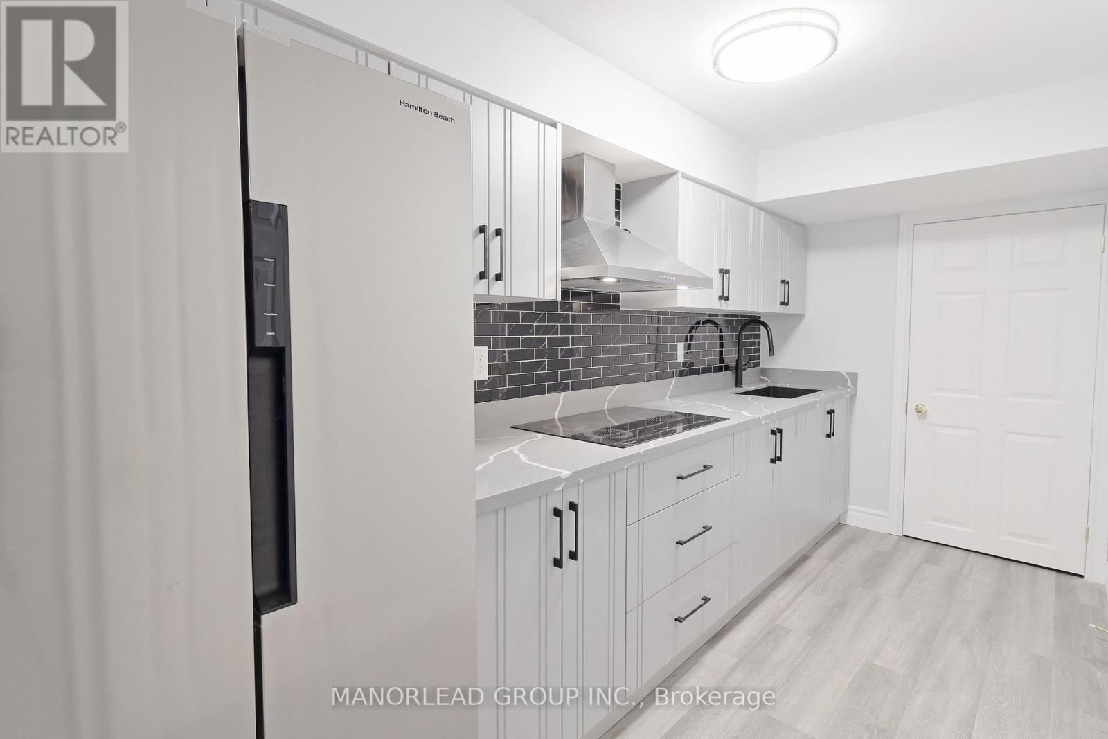 A kitchen with white cabinets and a black refrigerator.