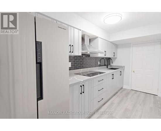 A kitchen with white cabinets and a black refrigerator.