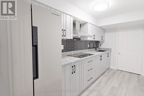 A kitchen with white cabinets and a black refrigerator.