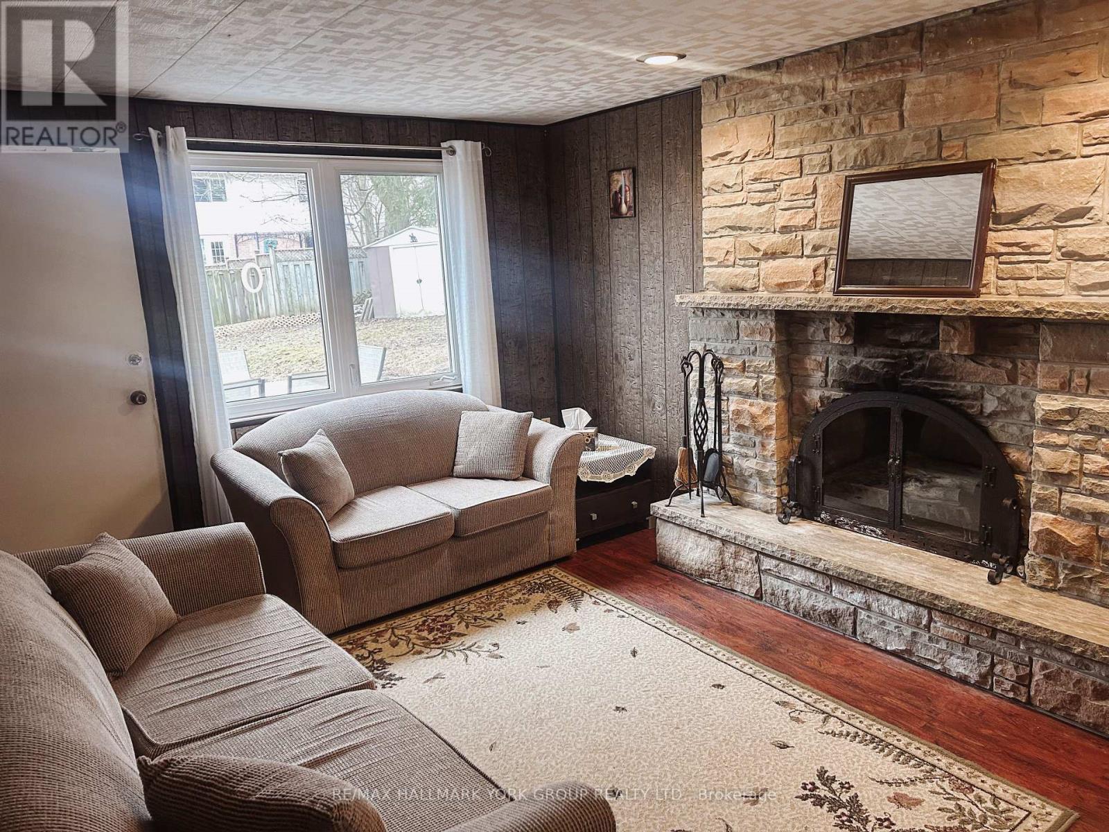 A living room with a stone fireplace and a flat screen TV above it.