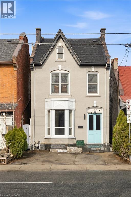 A house with a blue door is situated in front of a red brick building.