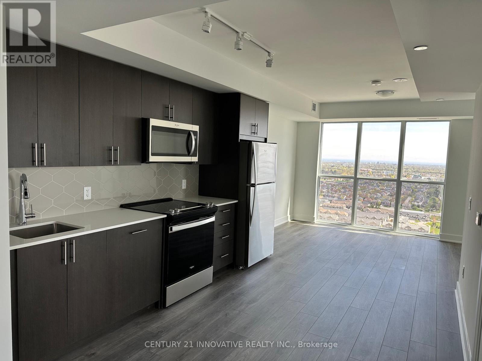 A modern kitchen with dark wood cabinets and stainless steel appliances.