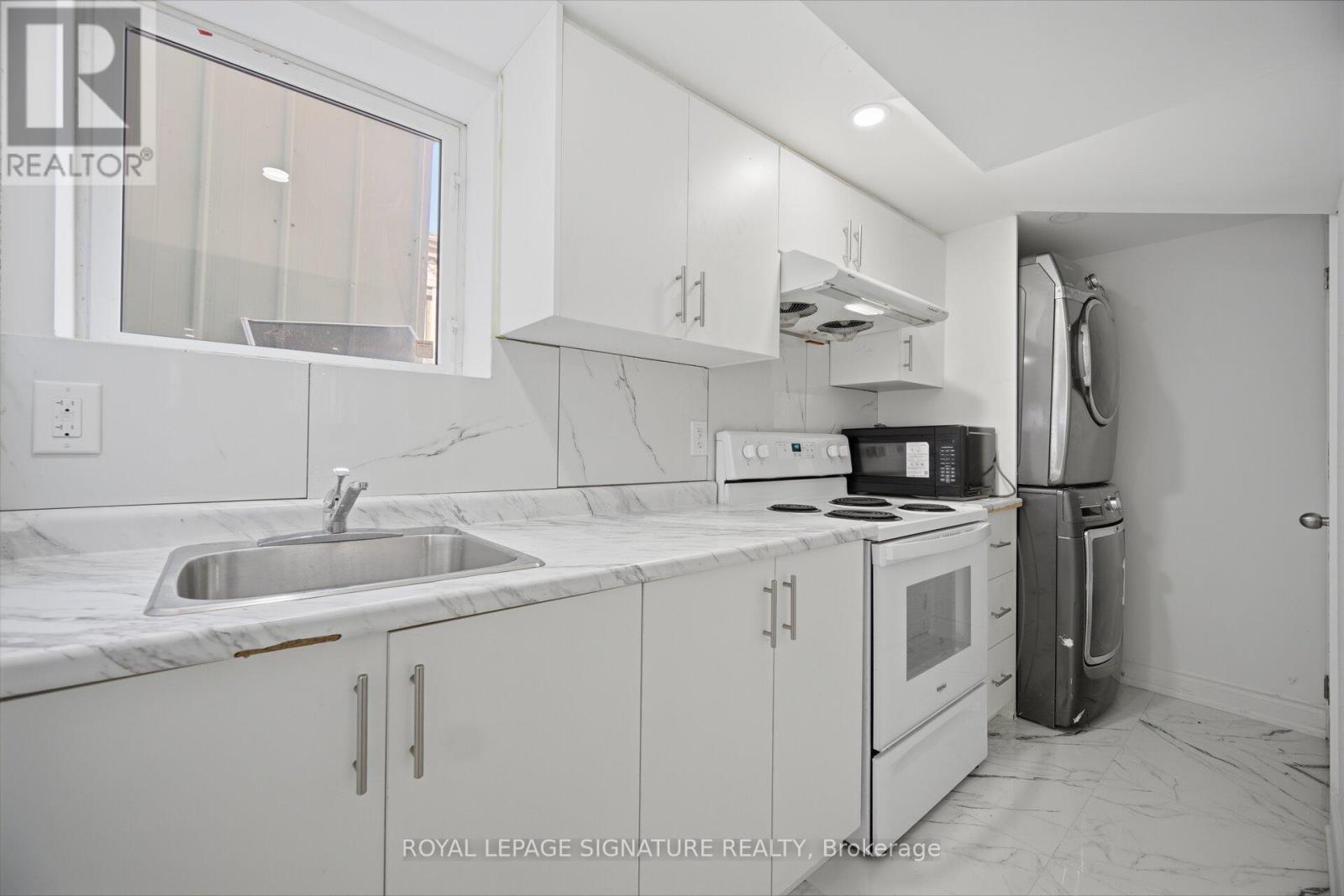 A kitchen with white cabinets and a marble countertop.