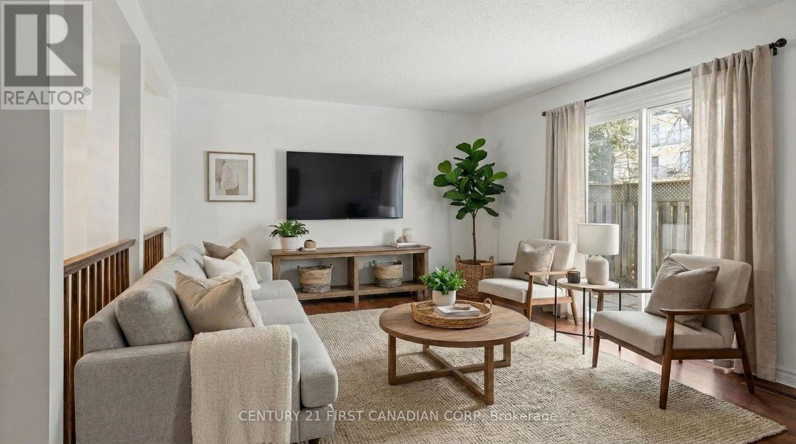 A living room with a grey couch, a wooden coffee table, and a flat screen TV mounted on the wall.
