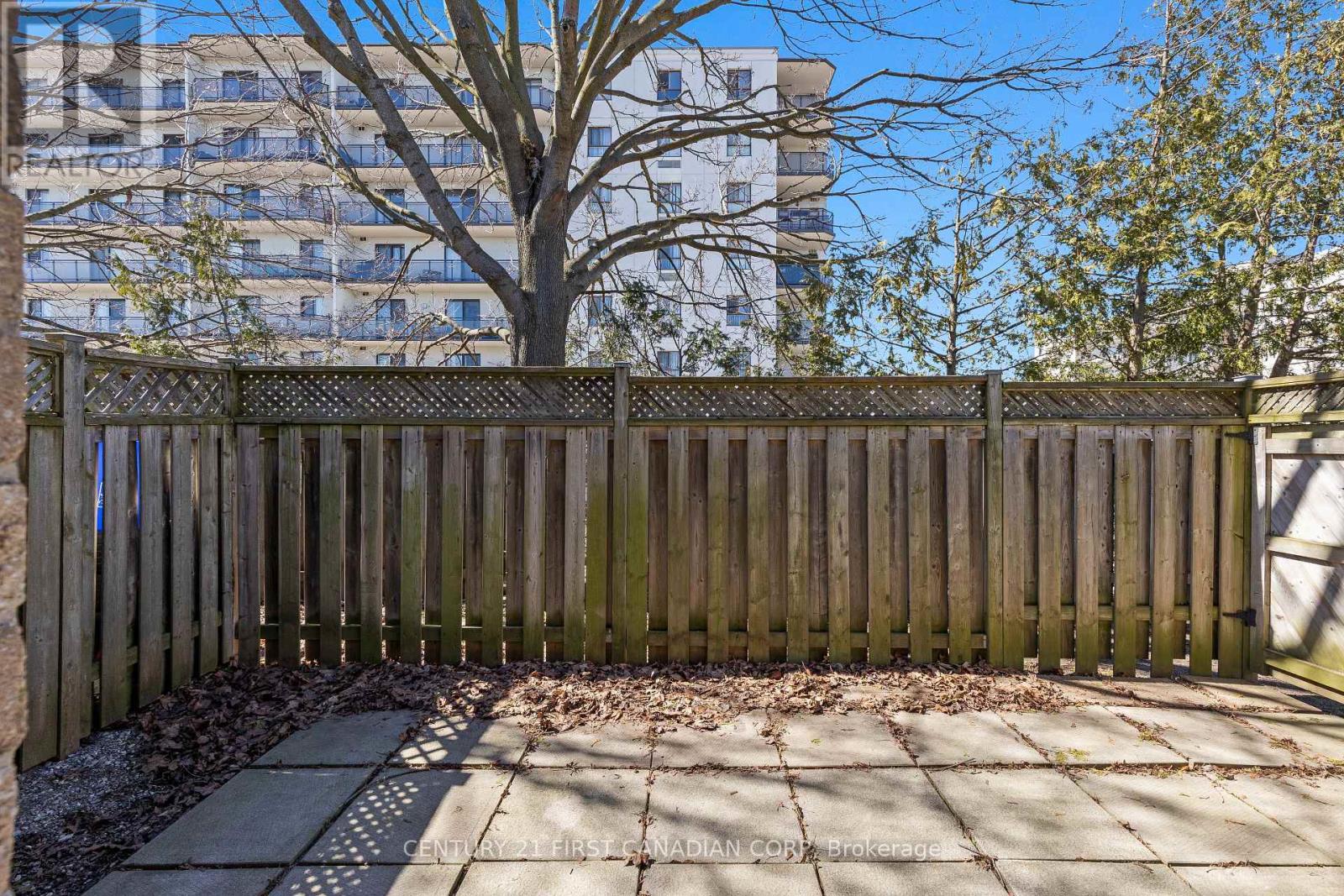 A wooden fence in front of a tree and a building.