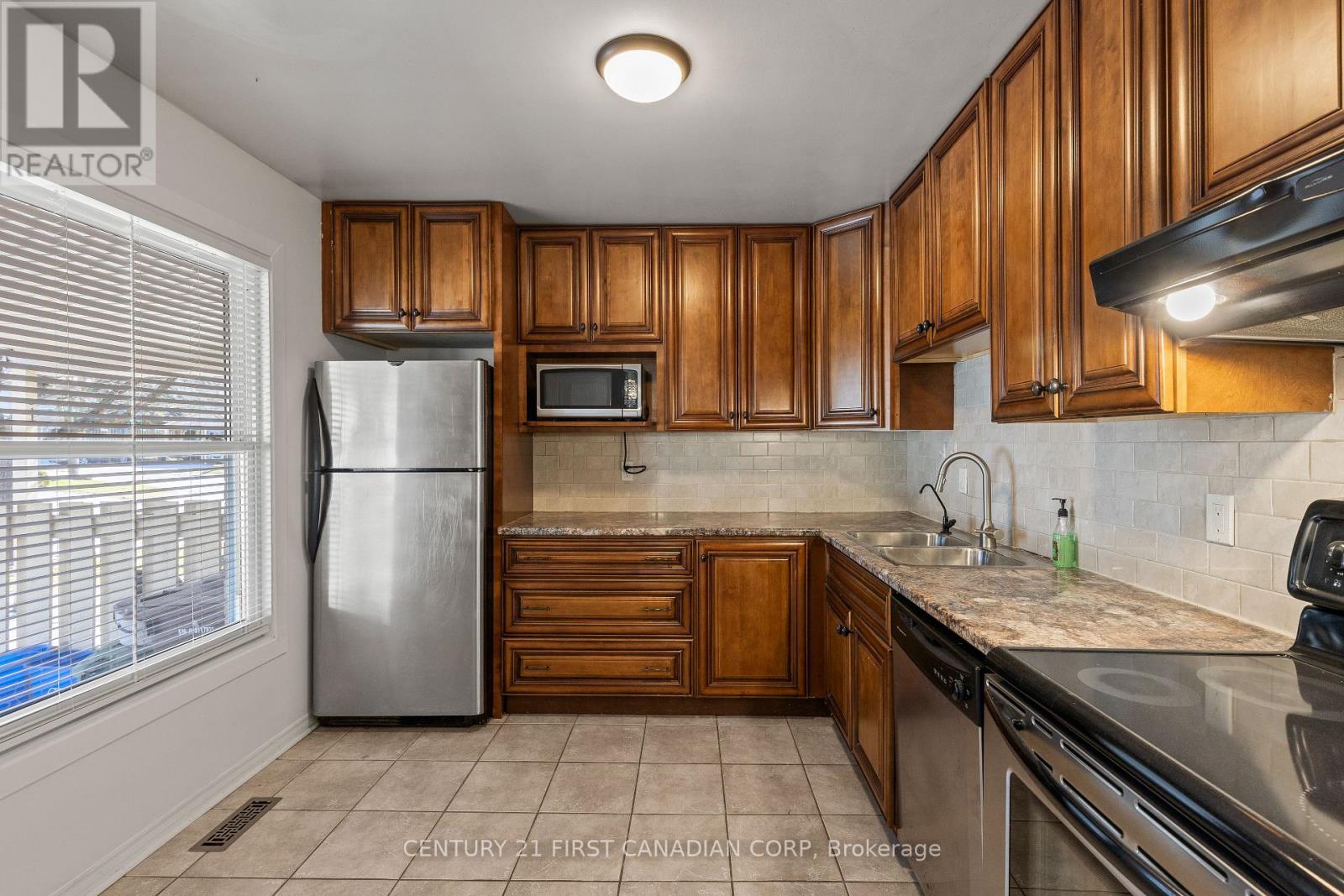 A kitchen with wooden cabinets and a stainless steel refrigerator.