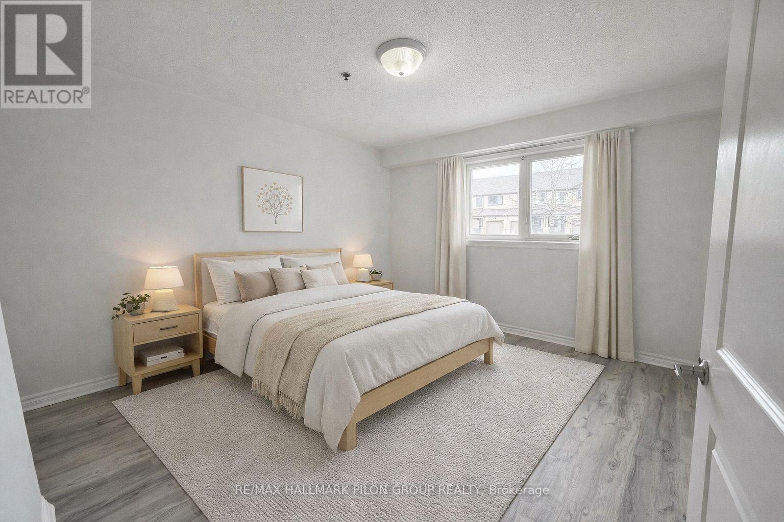 A bedroom with a bed, nightstand, and window.