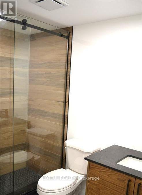 A toilet in a bathroom with a glass shower door.