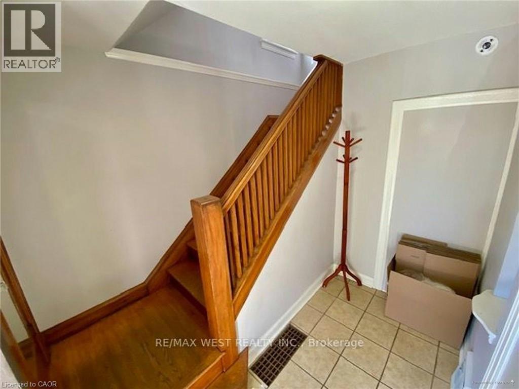 A wooden staircase with a white wall and a cardboard box on the floor.