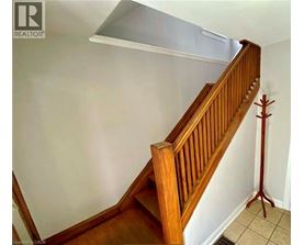 A wooden staircase with a white wall and a cardboard box on the floor.
