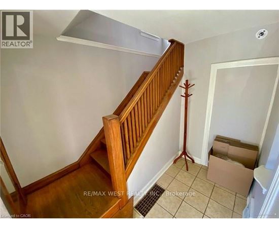 A wooden staircase with a white wall and a cardboard box on the floor.