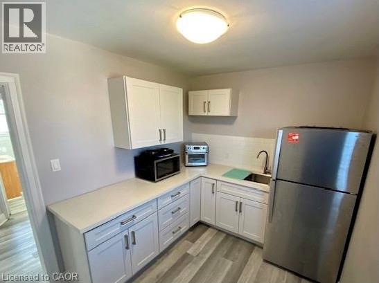 A kitchen with a refrigerator, microwave, and oven.