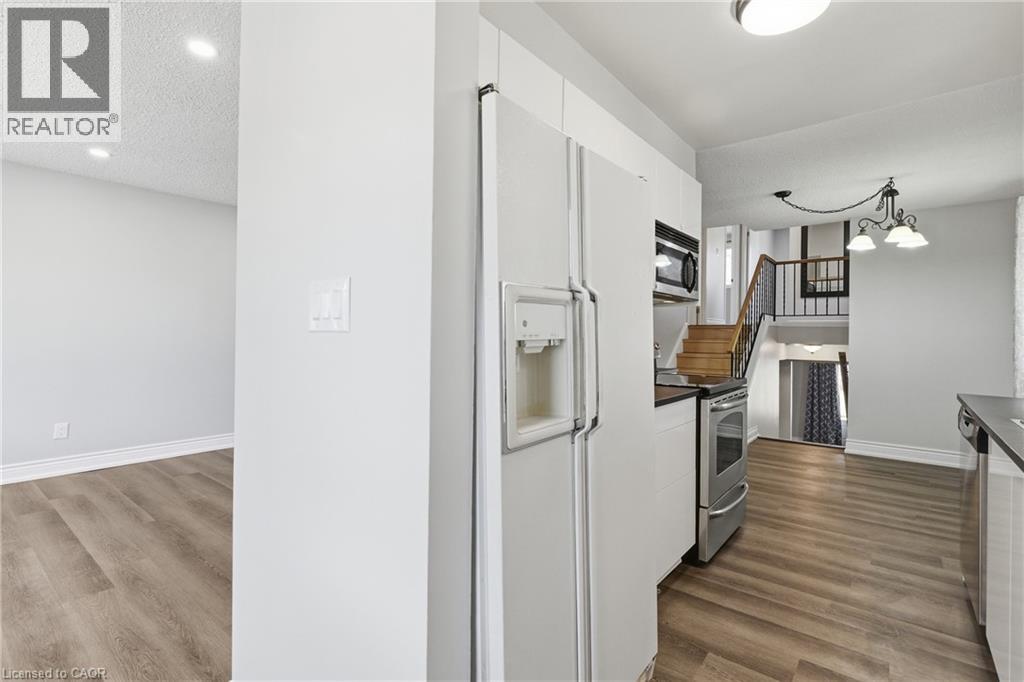 A white refrigerator in a kitchen with wood flooring.