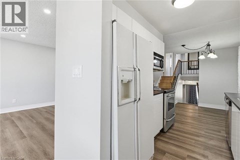 A white refrigerator in a kitchen with wood flooring.