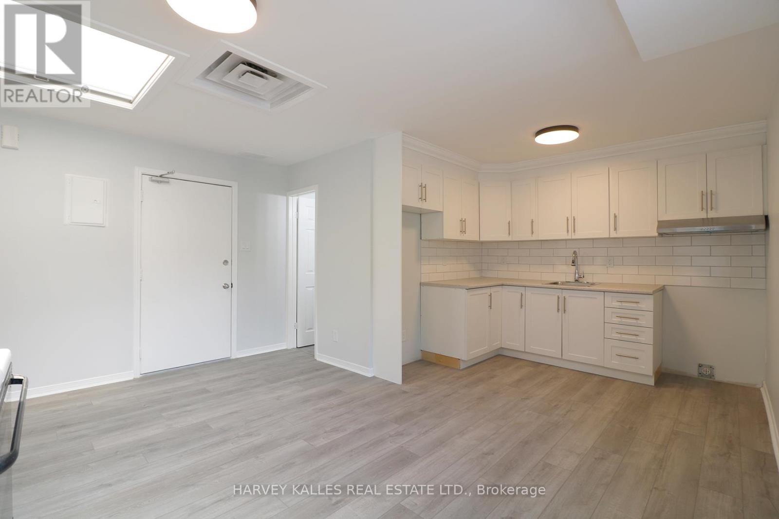 A spacious kitchen with white cabinets and a wooden floor.