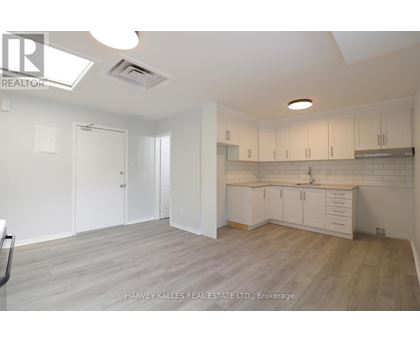 A spacious kitchen with white cabinets and a wooden floor.