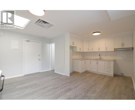 A spacious kitchen with white cabinets and a wooden floor.