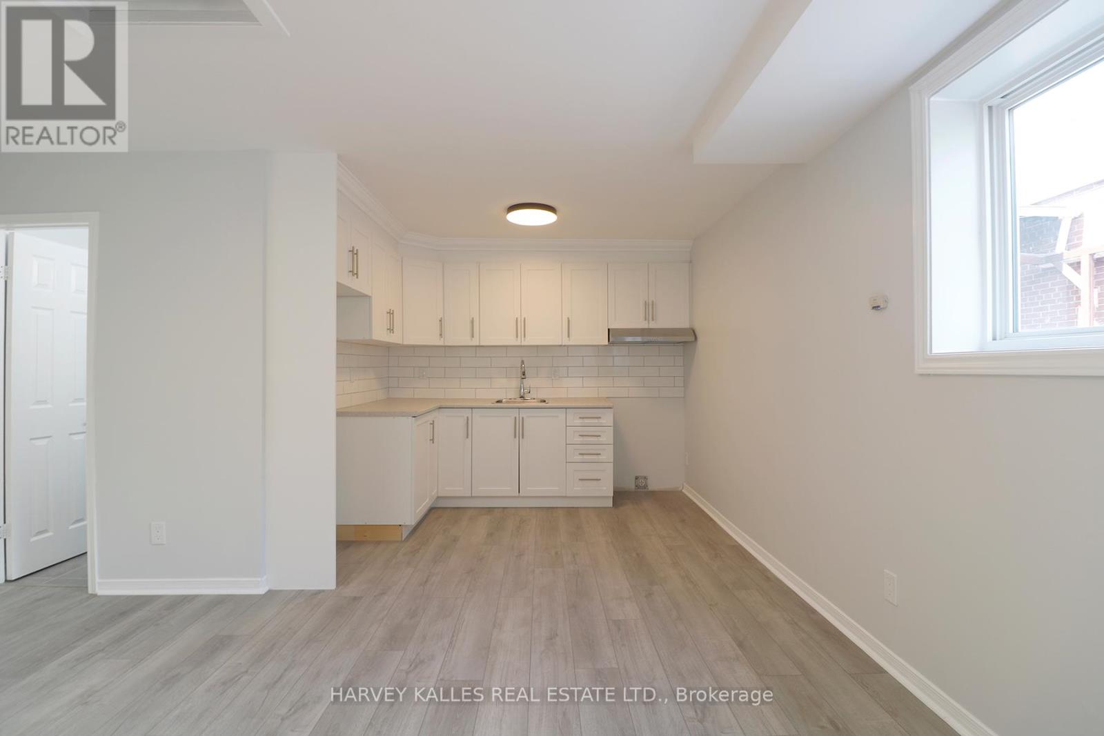 A spacious kitchen with white cabinets and a window.