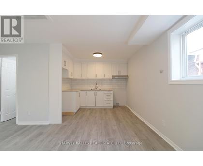 A spacious kitchen with white cabinets and a window.