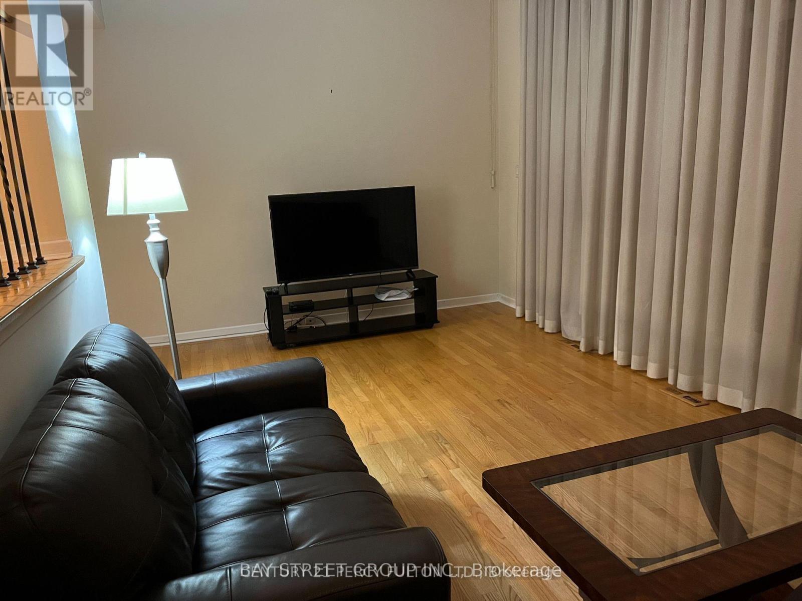 A black leather sofa sits in front of a television in a living room.